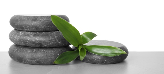 Photo of Black spa stones with bamboo on table against white background. Space for text