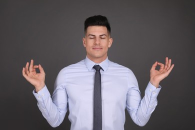 Photo of Businessman meditating on dark grey background. Personality concept