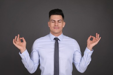 Businessman meditating on dark grey background. Personality concept