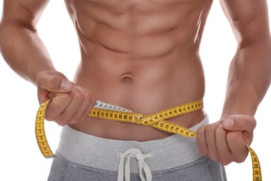 Photo of Shirtless man with slim body and measuring tape around his waist on white background, closeup