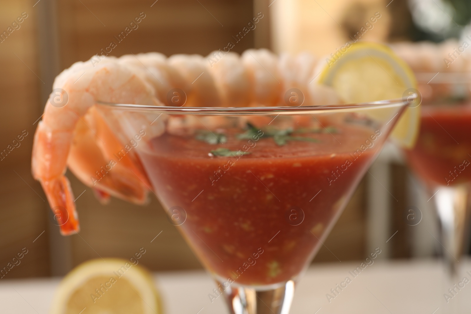 Photo of Tasty shrimp cocktail with sauce in glass on blurred background, closeup