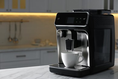 Modern electric coffee machine with cup on white countertop in kitchen