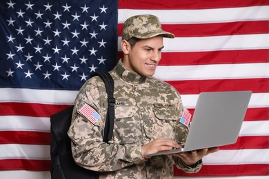Cadet with backpack and laptop against American flag. Military education