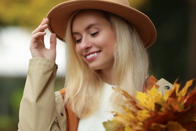 Portrait of happy woman with autumn leaves outdoors