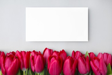 Photo of Many beautiful tulips and blank card on light grey background, flat lay