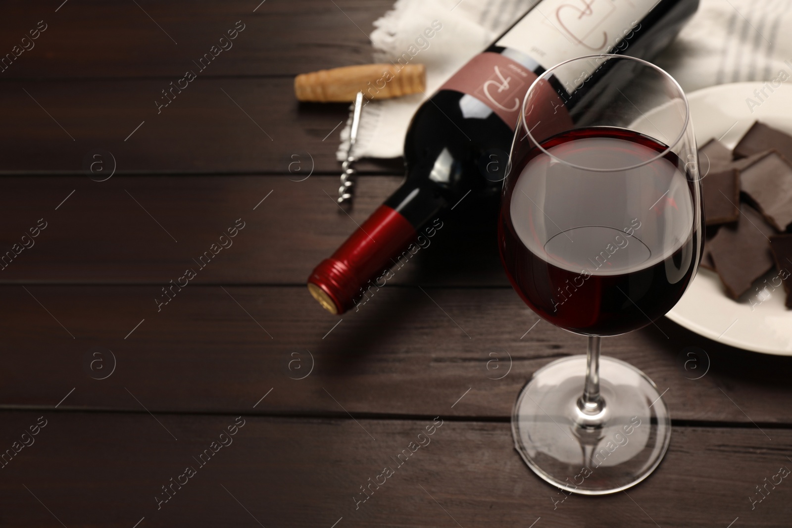 Photo of Tasty red wine and chocolate on wooden table. Space for text