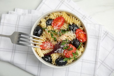 Photo of Bowl of delicious pasta with tomatoes, olives and cheese on white table, top view