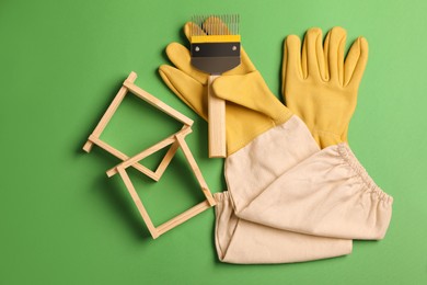 Photo of Beekeeping tools on green background, flat lay