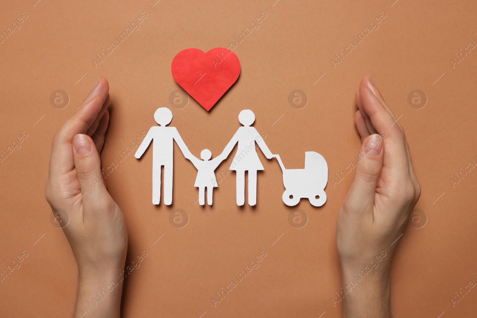 Photo of Woman protecting paper family figures and red heart on brown background, top view. Insurance concept