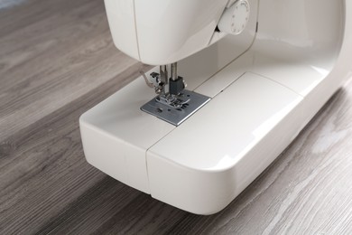 Photo of White sewing machine on wooden table, closeup