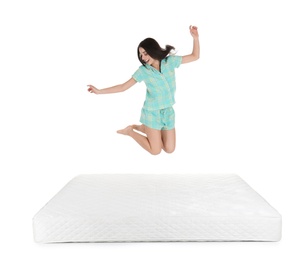 Young woman jumping on mattress against white background