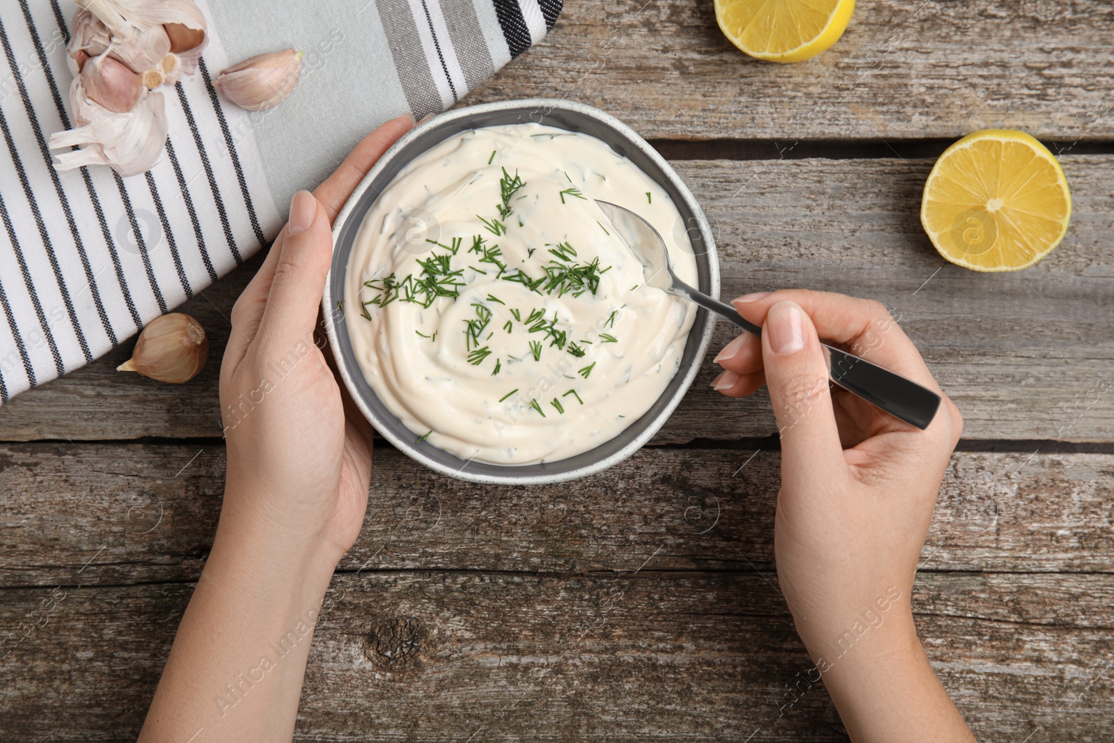 Photo of Woman preparing tasty creamy dill sauce at wooden table, top view