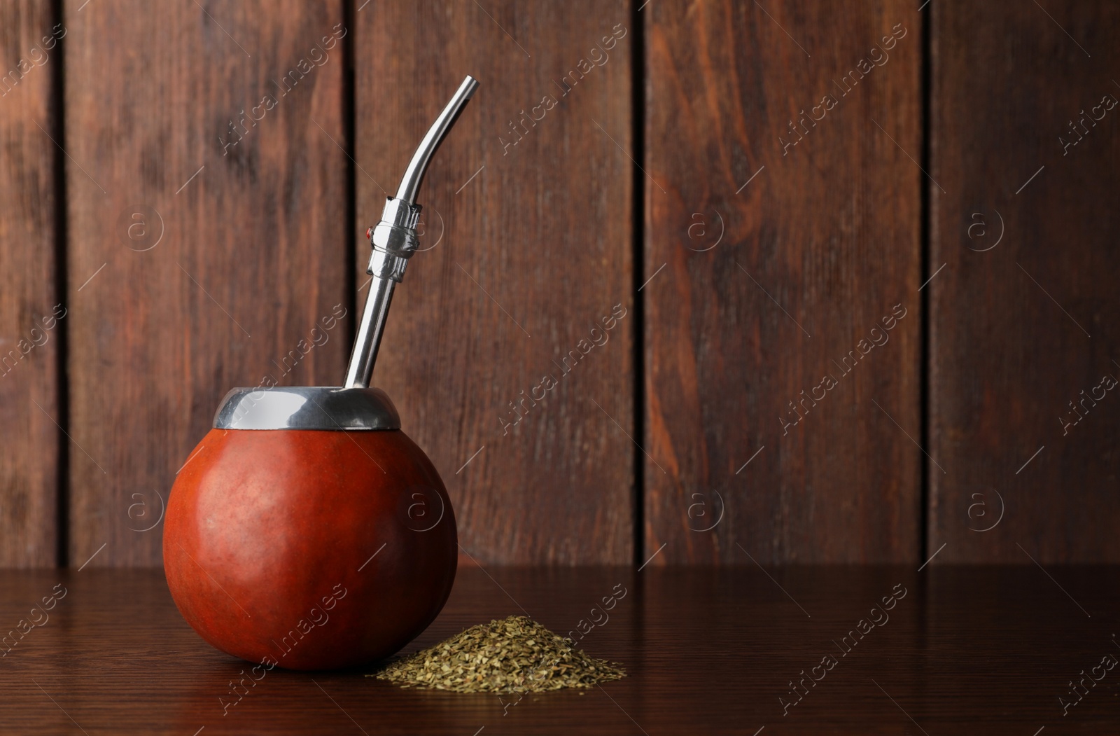 Photo of Calabash with mate tea and bombilla on wooden table. Space for text