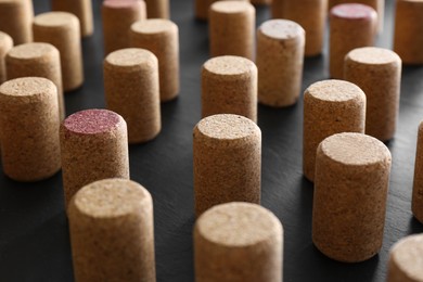 Photo of Many wine bottle corks on black table, closeup