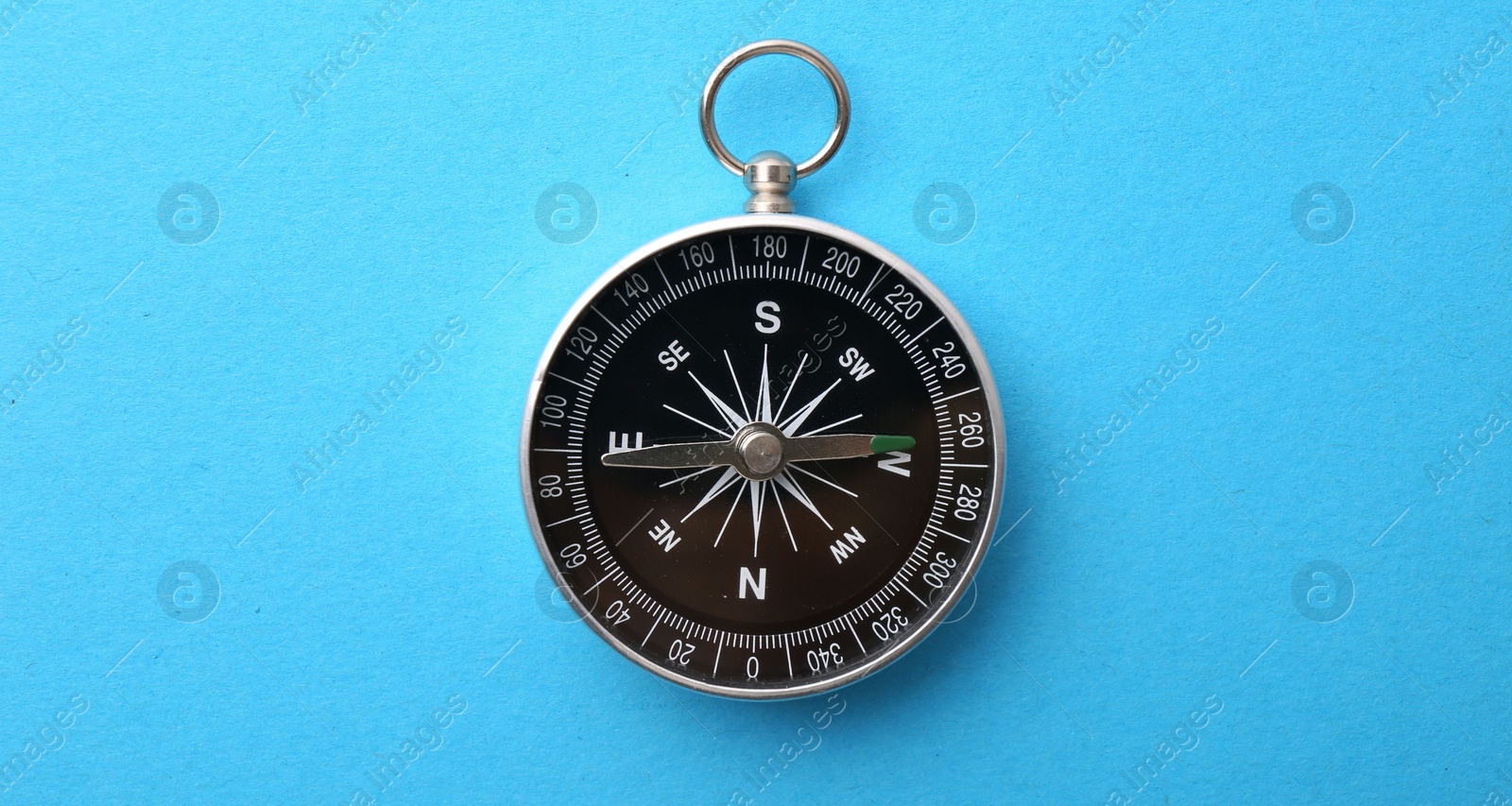 Photo of One compass on light blue background, top view