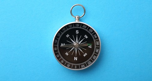Photo of One compass on light blue background, top view
