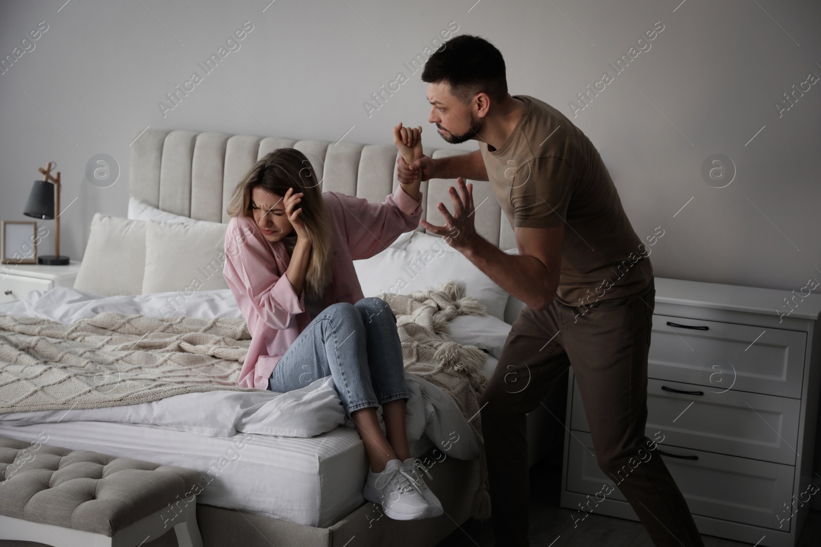 Photo of Man abusing scared woman at home. Domestic violence