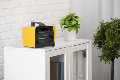 Photo of Modern electric fan heater near notebooks and houseplant on white table in room