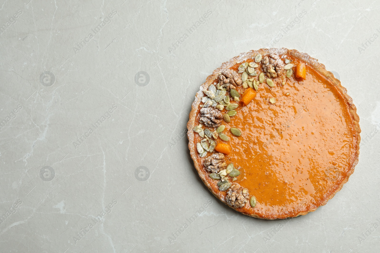 Photo of Delicious fresh homemade pumpkin pie on light grey marble table, top view. Space for text