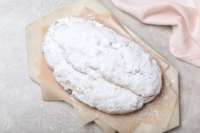 Photo of Delicious Stollen sprinkled with powdered sugar on light table, top view