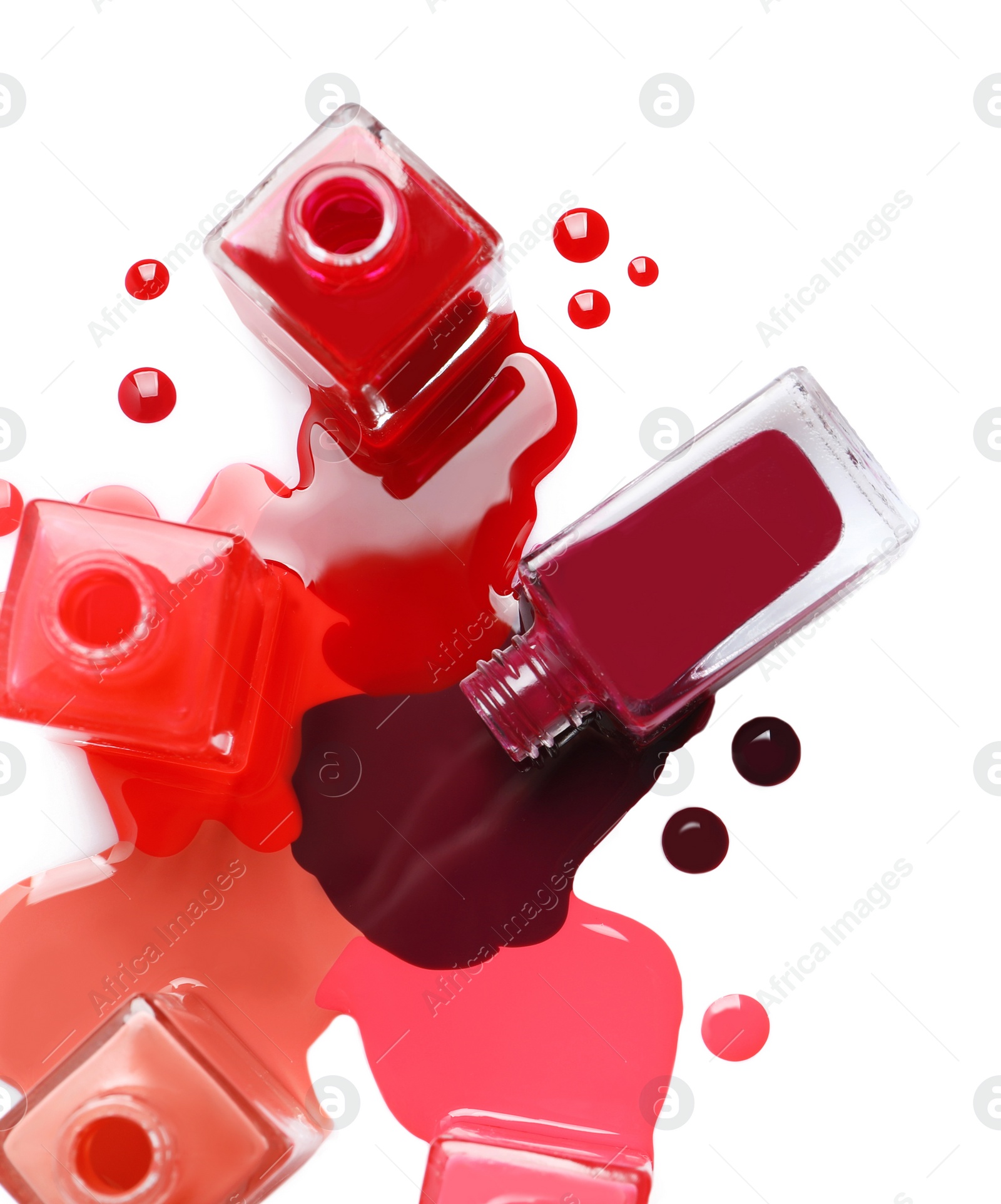 Photo of Spilled different nail polishes with bottles on white background, top view