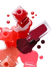 Spilled different nail polishes with bottles on white background, top view