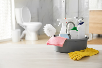 Photo of Cleaning supplies and toilet bowl in bathroom. Space for text