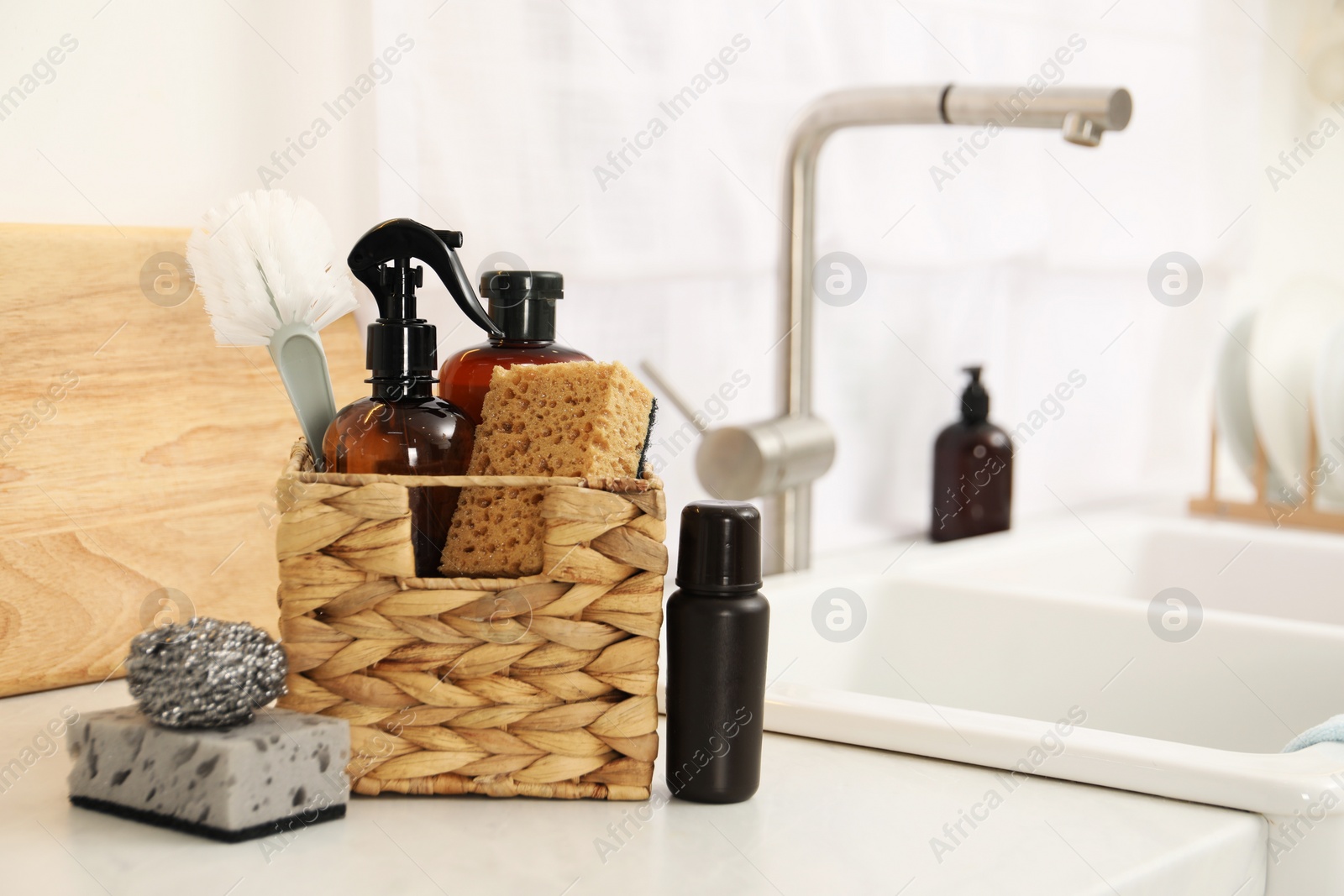 Photo of Different cleaning supplies in basket on countertop. Space for text