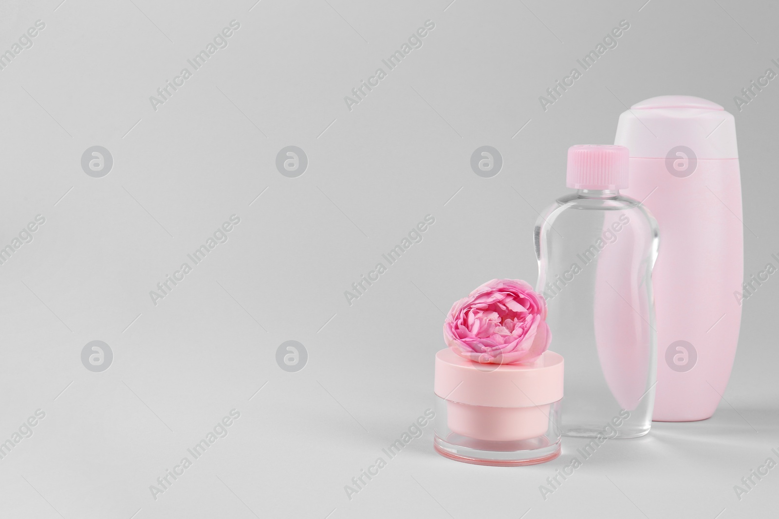 Photo of Different baby care products and beautiful flower on light grey background, space for text