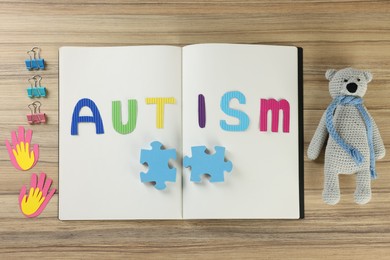 Photo of Flat lay composition of notebook with word Autism, clips and toys on wooden table