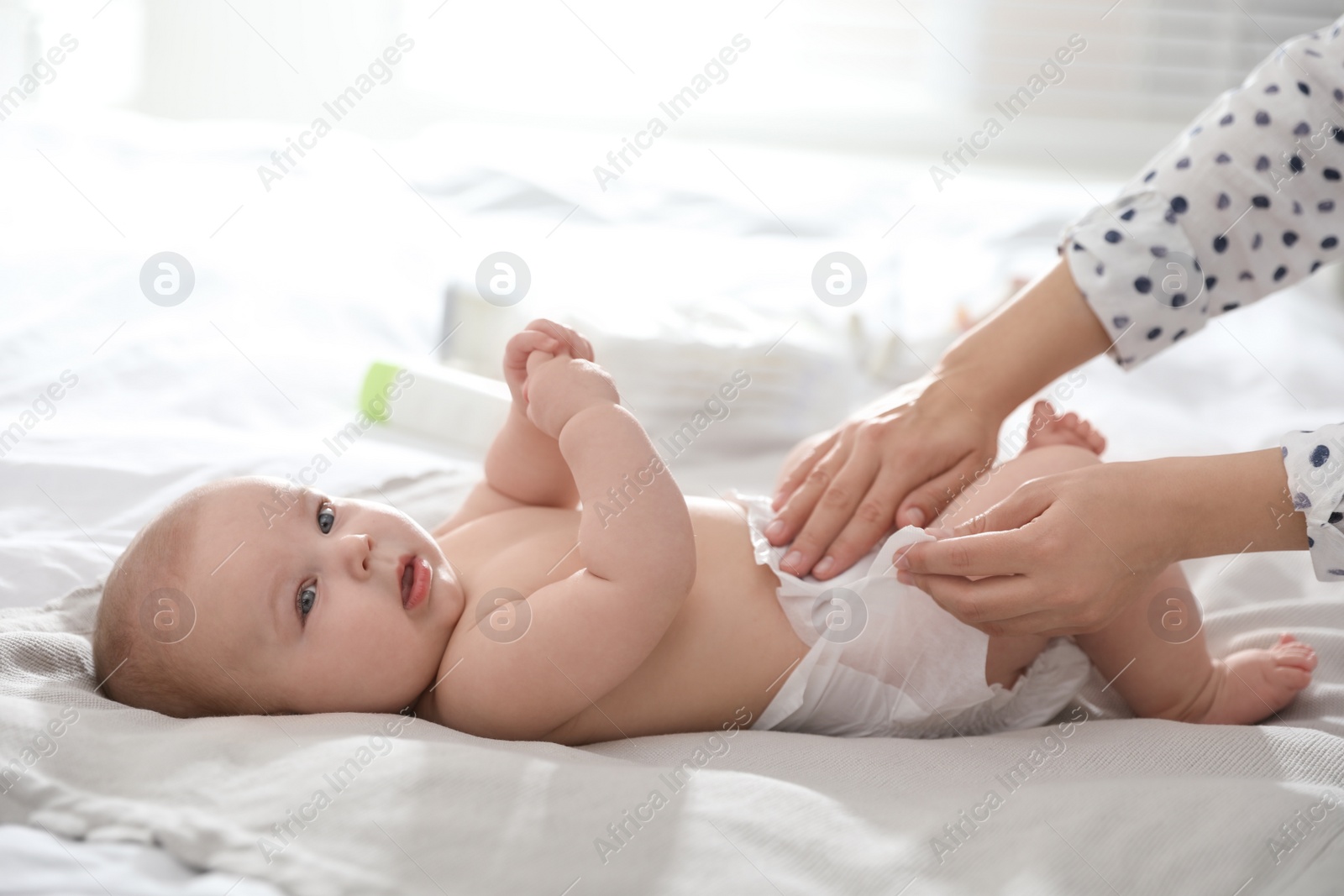 Photo of Mother changing her baby's diaper on bed