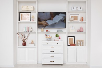 TV and shelves with different decor in room. Interior design