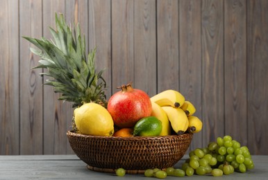 Photo of Wicker bowl with different ripe fruits on wooden table