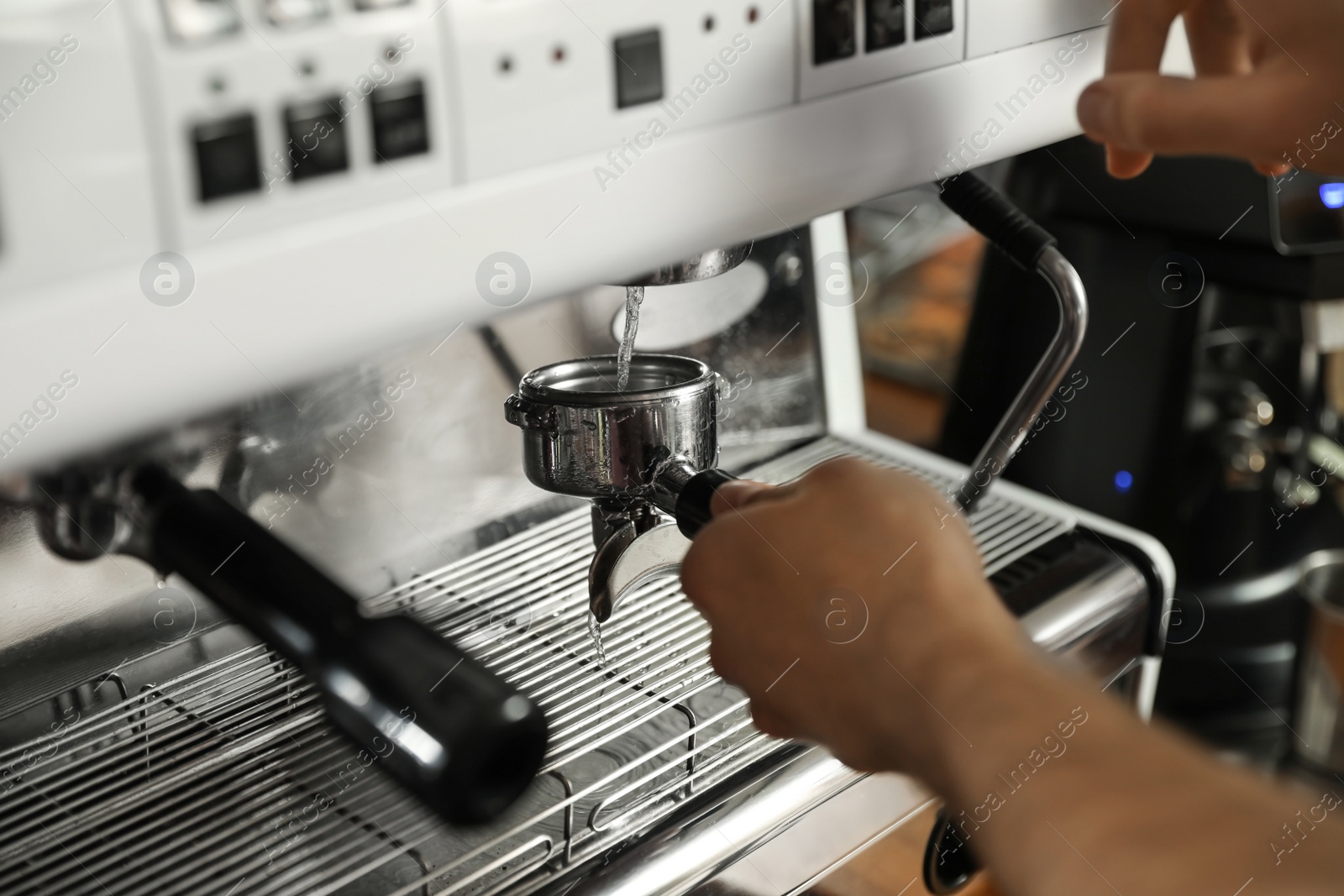 Photo of Barista cleaning portafilter at coffee machine in cafe, closeup