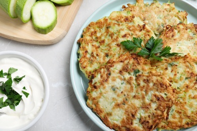 Delicious zucchini fritters served on light table, above view