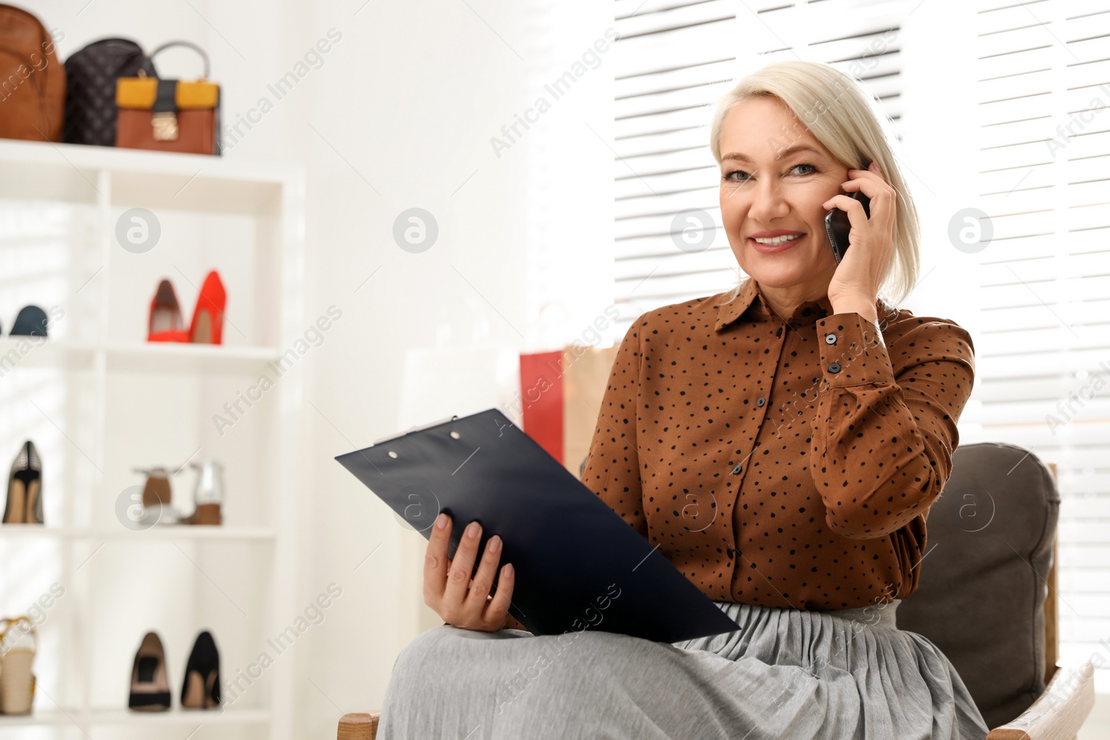 Photo of Female business owner talking on phone in boutique