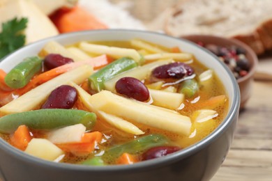 Photo of Bowl of delicious turnip soup on wooden table, closeup