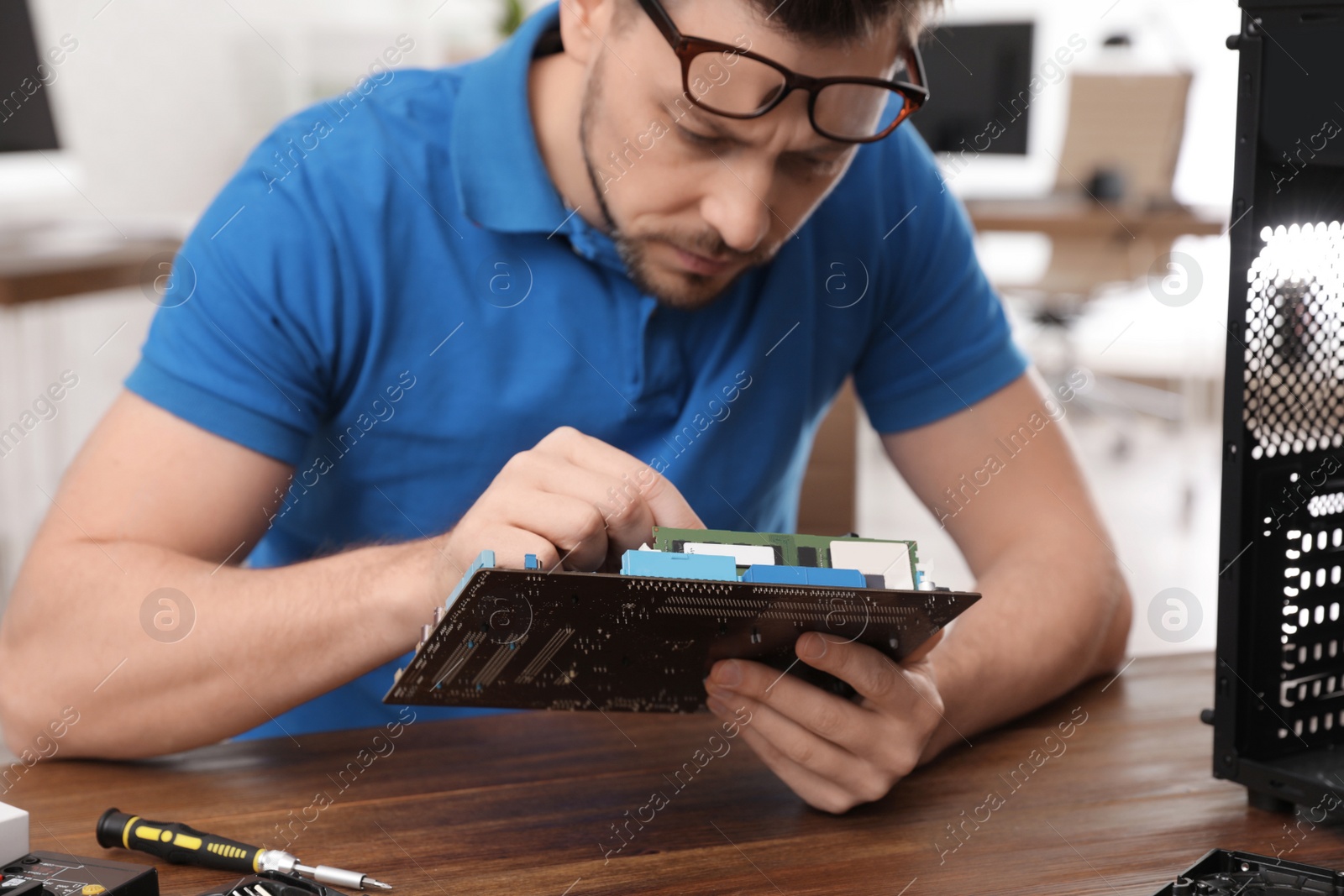 Photo of Male technician repairing computer at table indoors