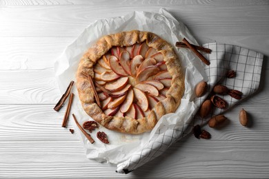 Photo of Delicious apple galette, cinnamon and pecans on white wooden table, flat lay