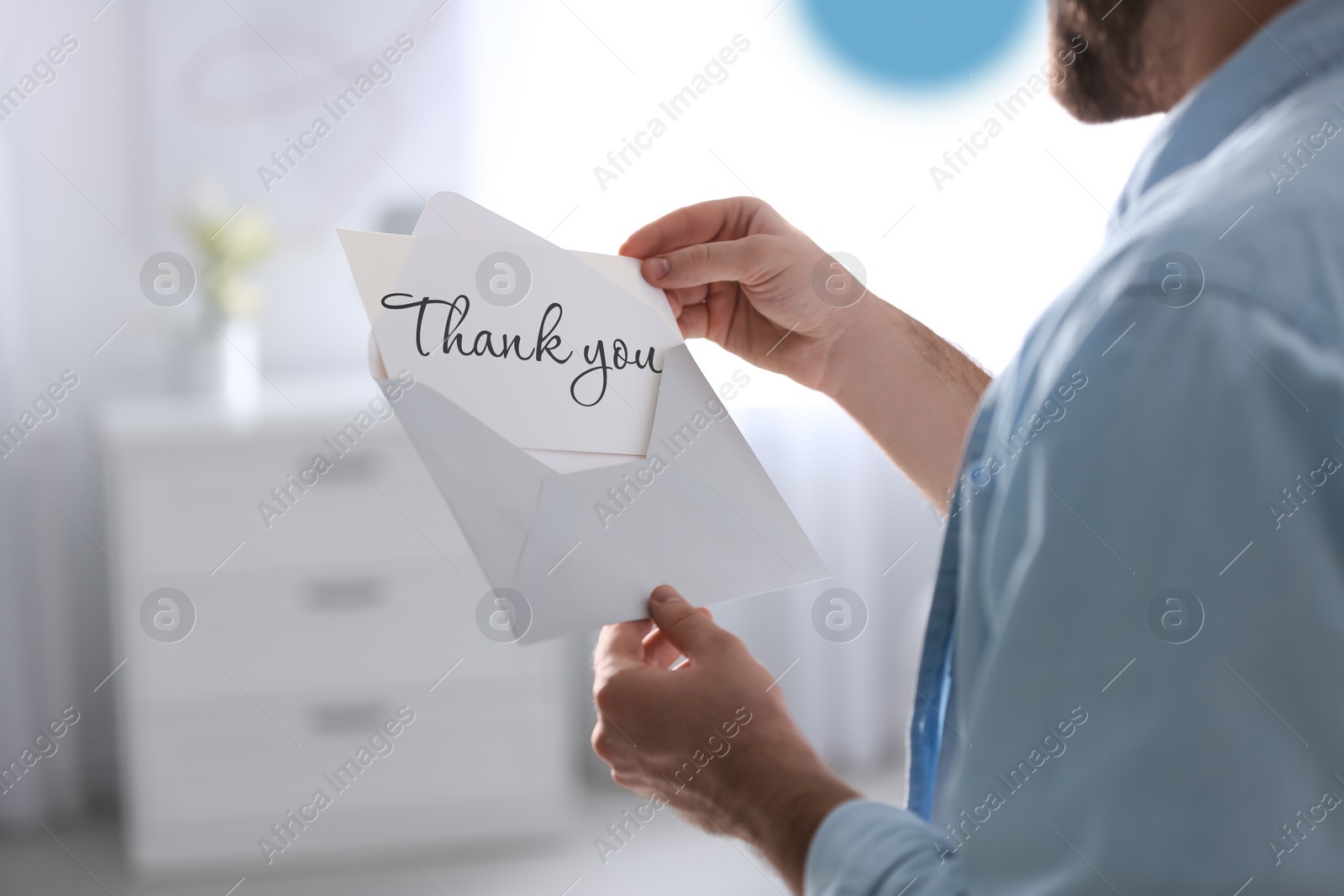 Image of Man reading card with phrase Thank You at home, closeup