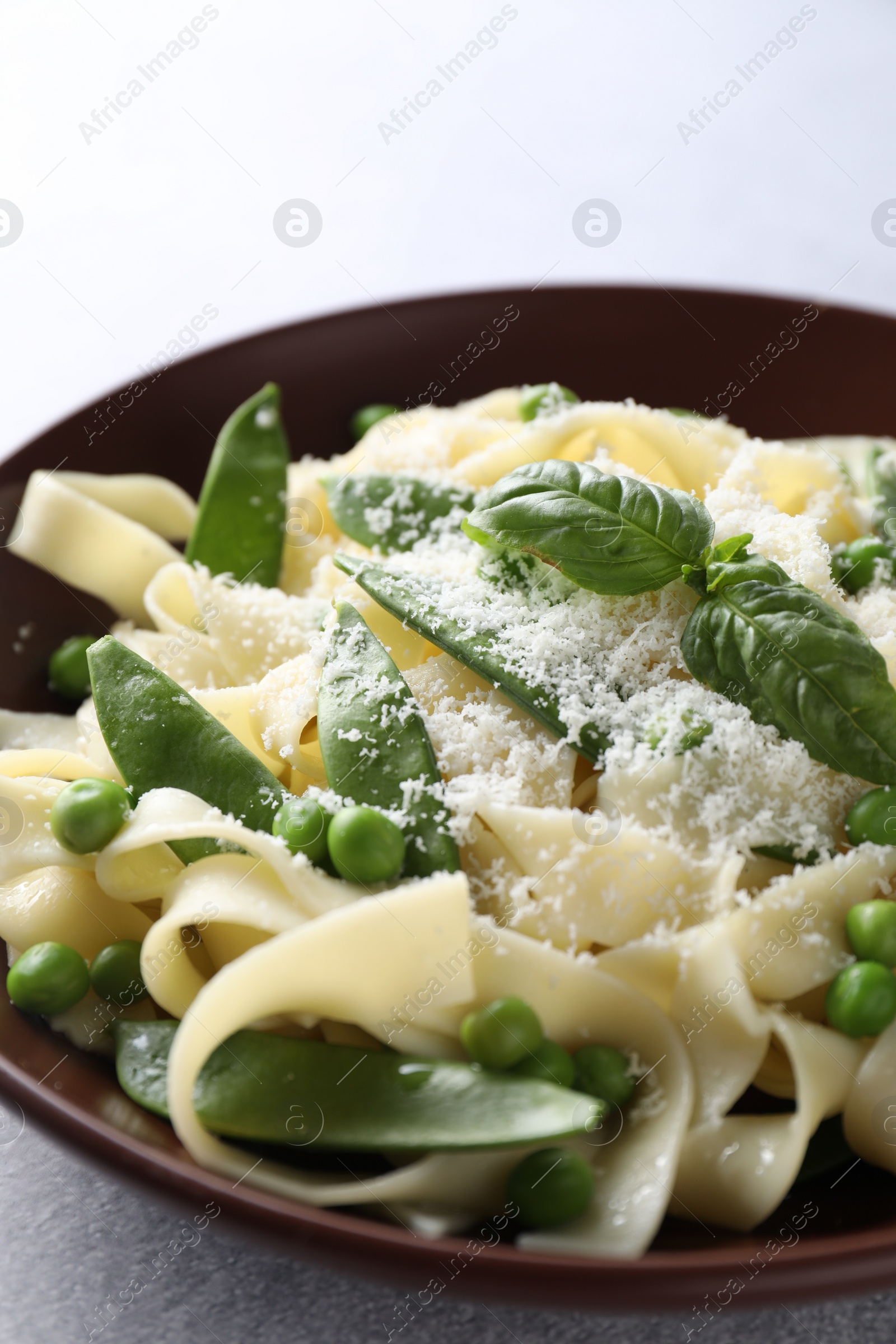 Photo of Delicious pasta with green peas and cheese on grey table, closeup