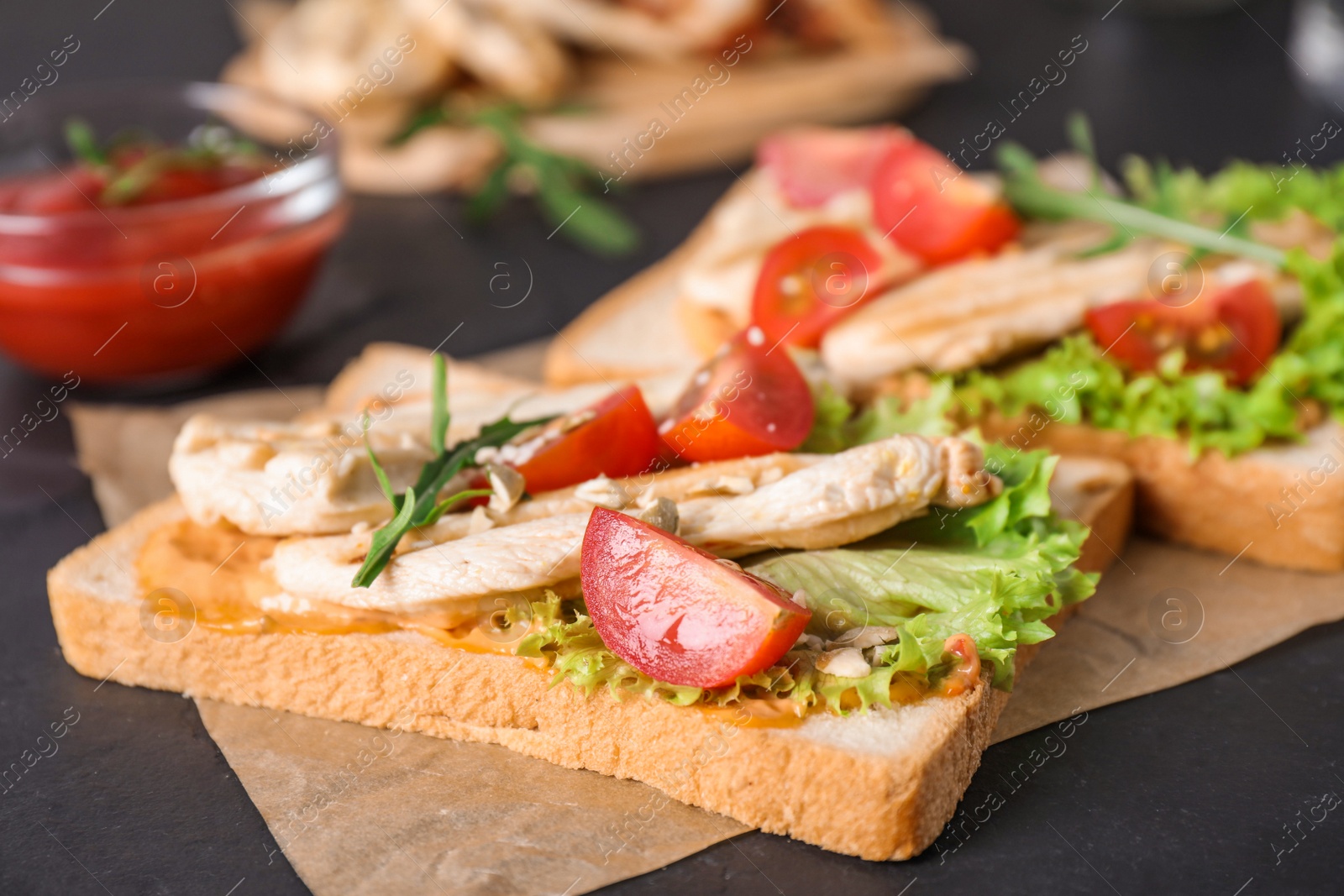 Photo of Delicious sandwiches with chicken on black table, closeup