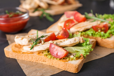 Delicious sandwiches with chicken on black table, closeup