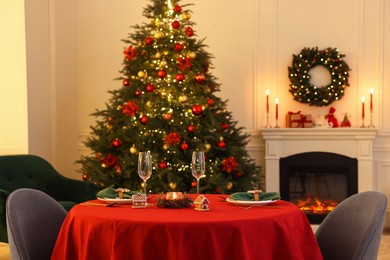 Photo of Cozy living room with Christmas tree near fireplace and table served for celebration. Interior design