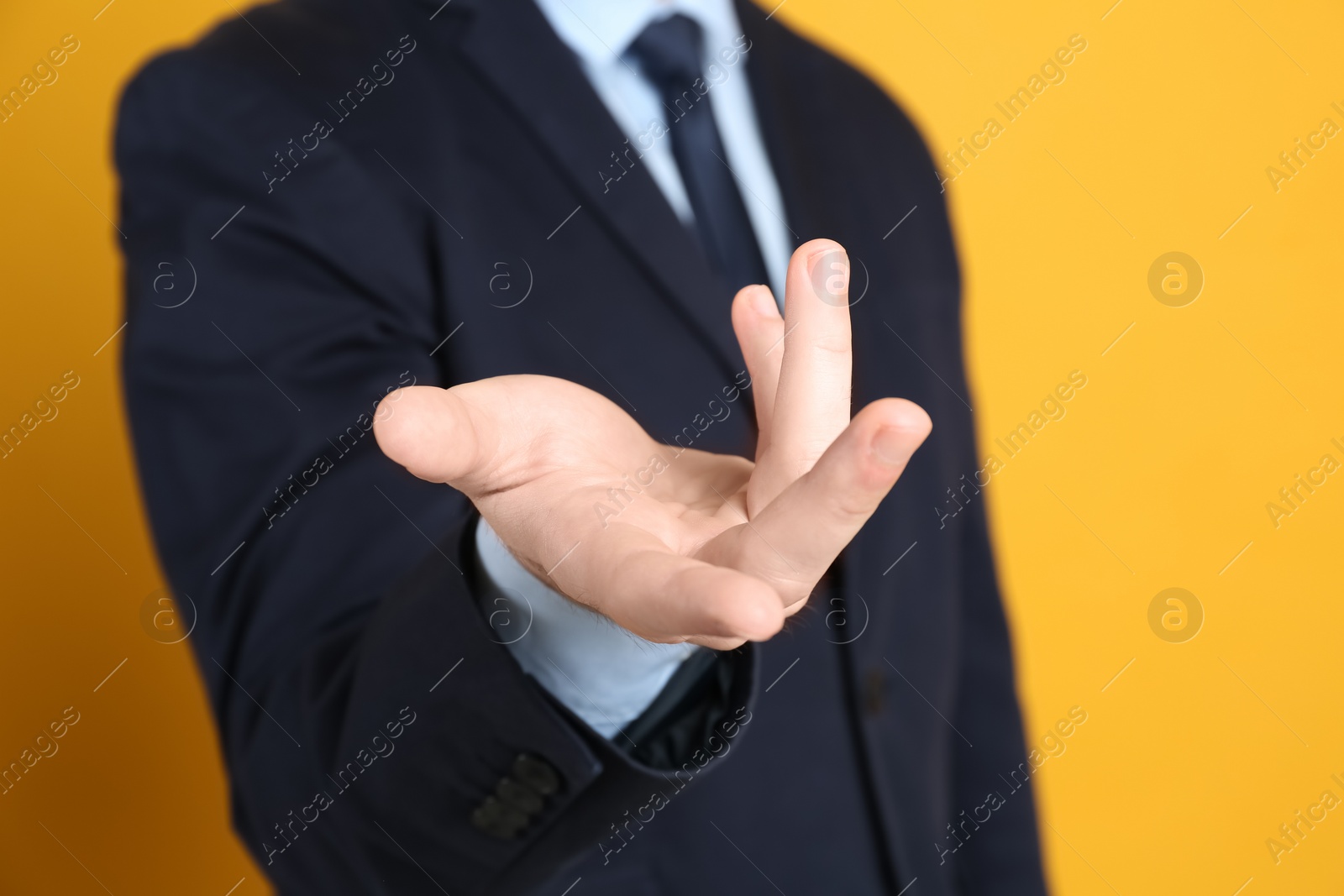 Photo of Businessman showing something against orange background, focus on hand