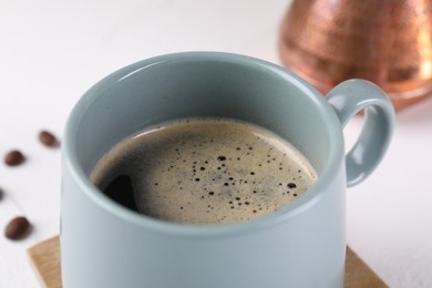 Delicious coffee in cup on white table, closeup