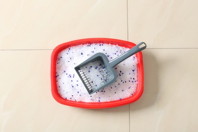 Photo of Cat tray with crystal litter and scoop on floor, top view