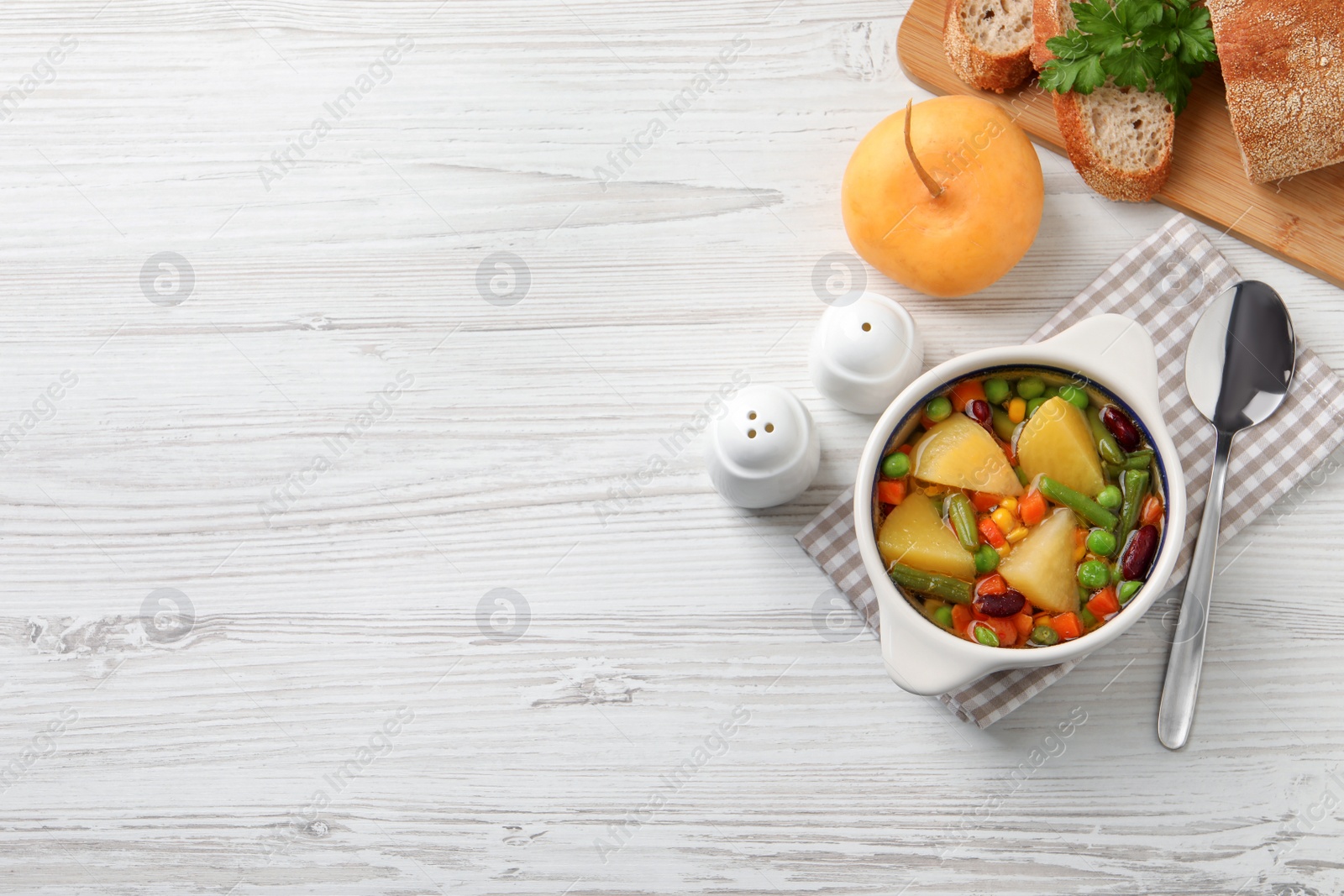 Photo of Bowl of delicious turnip soup served on white wooden table, flat lay. Space for text