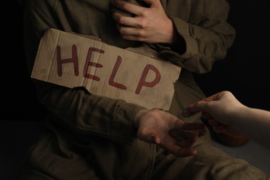 Photo of Woman giving coins to homeless with help sign, closeup. Charity and donation