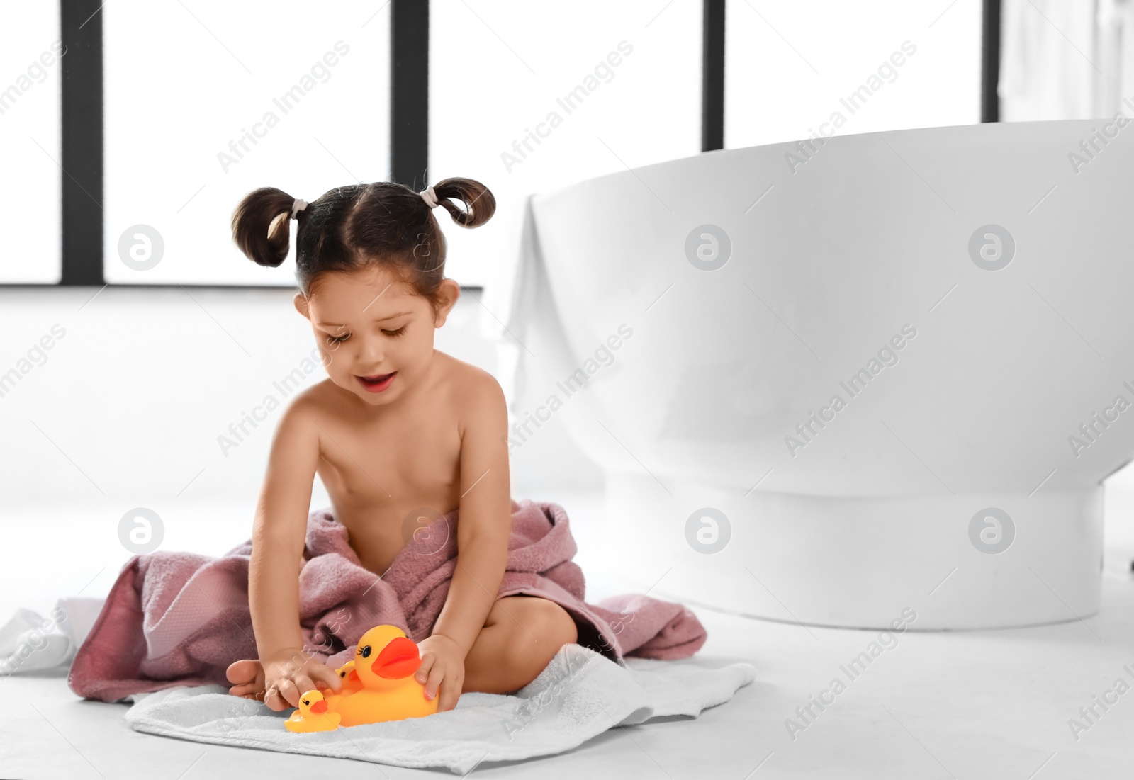 Photo of Cute little girl near tub in bathroom. Space for text